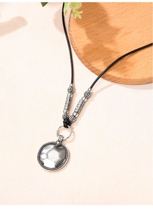 Détail du pendentif disque argenté rétro avec texture martelée et cordon noir à perles