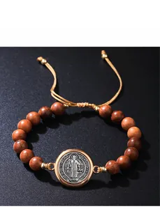 Makro-Detail des verstellbaren Holzperlenarmbands mit religiöser Benediktusmedaille