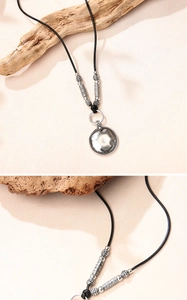 Détail du pendentif disque en argent vintage avec texture martelée et cordon tressé