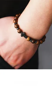 Gros plan d'un bracelet en perles de bois pour homme avec croix porté au poignet