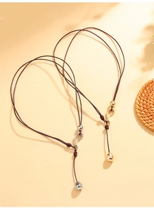 Detail of handmade brown cord necklaces with gold and silver teardrop pendants