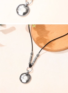 Détail d'un collier avec pendentif argenté géométrique et cordon tressé noir