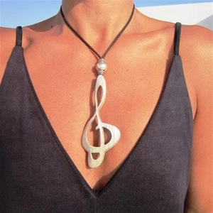 Vintage silver musical G-clef pendant necklace with black cord on model neck