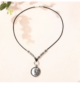 Détail d'un pendentif disque argenté rétro avec texture martelée et collier perlé
