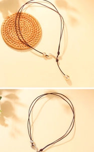 Detail of dark brown leather cord necklace with matte gold S-hook and teardrop pendant