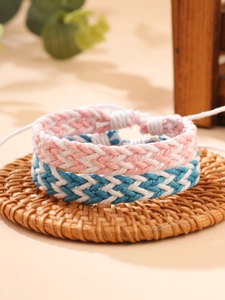 Dettaglio di braccialetti intrecciati rosa e blu su un sottobicchiere in rattan