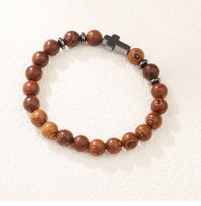 Détail du bracelet en perles de bois avec pendentif croix en hématite sur fond texturé