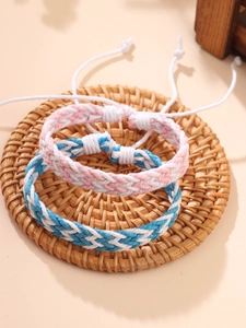 Dettaglio dei braccialetti intrecciati rosa e blu su un sottobicchiere di rattan