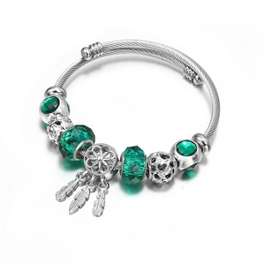 Detail of bohemian dreamcatcher bangle with green crystal beads and feather charms