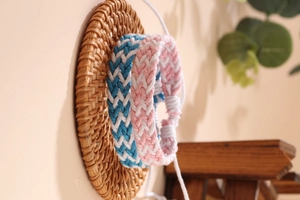 Dettaglio di braccialetti intrecciati a mano in blu e rosa su un vassoio di rattan