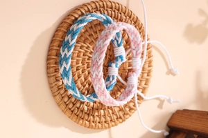 Dettaglio dei braccialetti di coppia intrecciati a mano con cordino regolabile blu e rosa