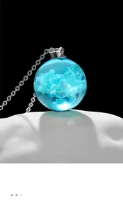 Macro shot of a clear resin ball pendant featuring realistic blue sky and white clouds