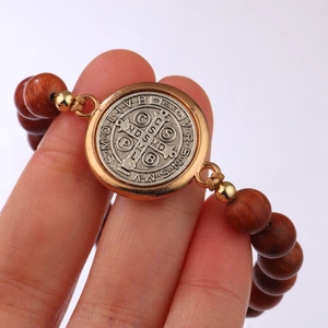 Adjustable St. Benedict Medal bracelet with wood beads and gold accents on white background