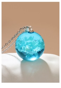 Macro shot of luminous blue resin ball necklace with realistic white cloud textures