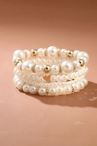 Detail of four-piece pearl bracelet set featuring gold heart pendant and round beads