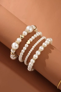 Macro detail of 4-piece pearl bracelet set with gold heart charm and textured beads