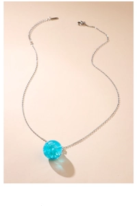 Detailed view of luminous blue resin sphere necklace with clouds and silver chain