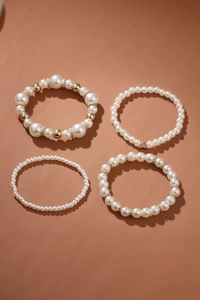 Detail view of four-piece pearl bracelet set with gold heart charms and elastic bands
