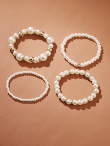 Detail of four-piece pearl bracelet set with gold heart charm on warm background