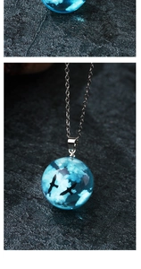 Detailed view of luminous resin ball necklace with blue sky clouds and bird silhouette