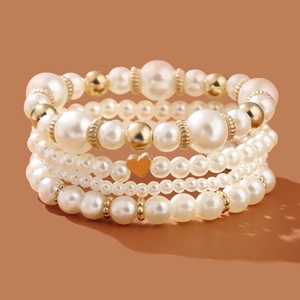 Chic four-layer beaded pearl bracelet set featuring a gold heart pendant and metallic accents