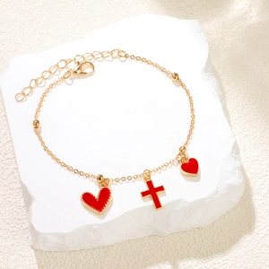 Bracelet doré avec pendentifs cœur rose et croix présenté sur une pierre blanche chic