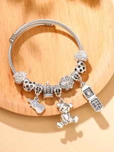 Detail view of silver cable charm bracelet with crown, clover and bear pendants