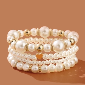 Elegant four-piece pearl bracelet set for women featuring gold heart charms and beads