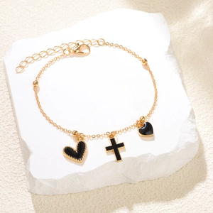 Bracelet chaîne dorée avec breloques cœur et croix noires sur support en pierre