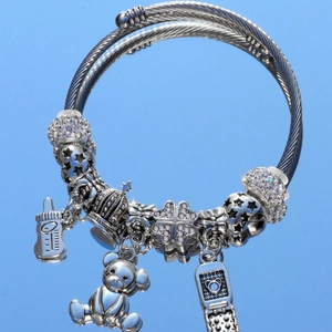 Silver-tone beaded charm bracelet with bear and star pendants on a blue background