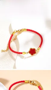 Detailed view of red woven string bracelet with golden clover charm and adjustable clasp