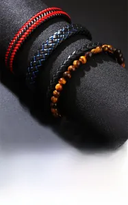 Detailed view of woven leather bracelets and tiger eye stone beads on a black cylinder