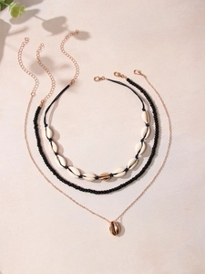 Three-layer bohemian necklace set with natural shells and black beads on pink background