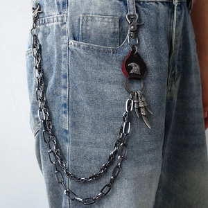 Punk style layered metal pant chain with eagle pendant and leather tag on light jeans