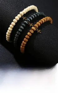 Macro detail of three-piece wood bead bracelets featuring gold cross charms on black display
