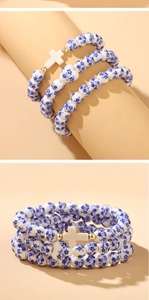 Three-piece ceramic bead bracelet set with blue floral patterns, cross, and heart charms