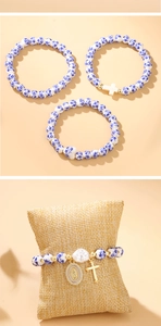 Detailed macro view of ceramic bead bracelet with baroque pearl and golden cross charms