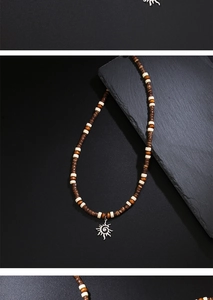 Close-up of bohemian wood bead necklace with silver sun totem pendant on dark stone