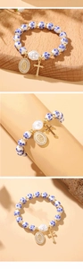 Close-up of ceramic beads bracelet with golden cross, virgin mary and baroque pearl