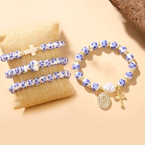 Blue and white porcelain bead bracelets with gold cross charms on a rustic display