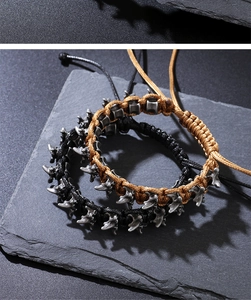 Close-up of black and brown braided punk bracelets with silver dragon bone alloy charms