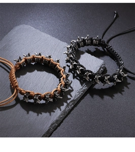 Close-up of punk style dragon bone braided bracelets in black and brown on a rocky surface
