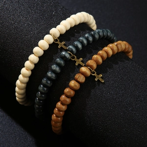 Three-piece wood bead bracelet set with small gold cross charms in multiple colors