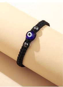 Dettaglio del bracciale in corda nera intrecciata con occhio greco blu e perline di metallo