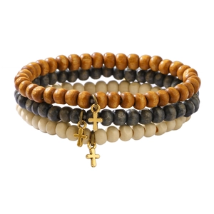Three-piece stackable wooden bead bracelets featuring golden cross pendants on white background
