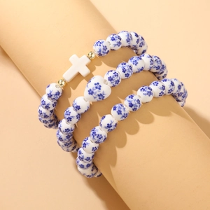 Three-piece ceramic bead bracelet set with blue floral patterns and a white cross charm