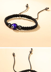 Dettaglio del bracciale intrecciato nero regolabile con perlina occhio blu e inserti metallici