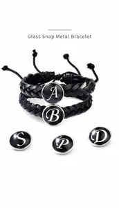 Détail du bouton pression en verre à 26 lettres sur un bracelet en cordon tissé noir