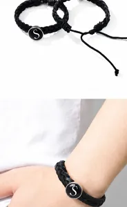 Détail du bracelet tressé noir réglable avec insert en pierre noire et lettre S