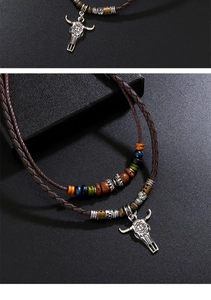 Detail showing carved metal bull skull pendant and colorful wooden beads on braided leather necklace